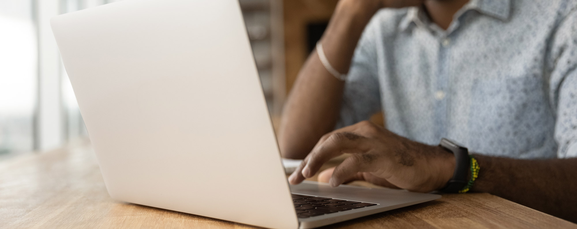 A close up photo of a man's hands typing on a computer.